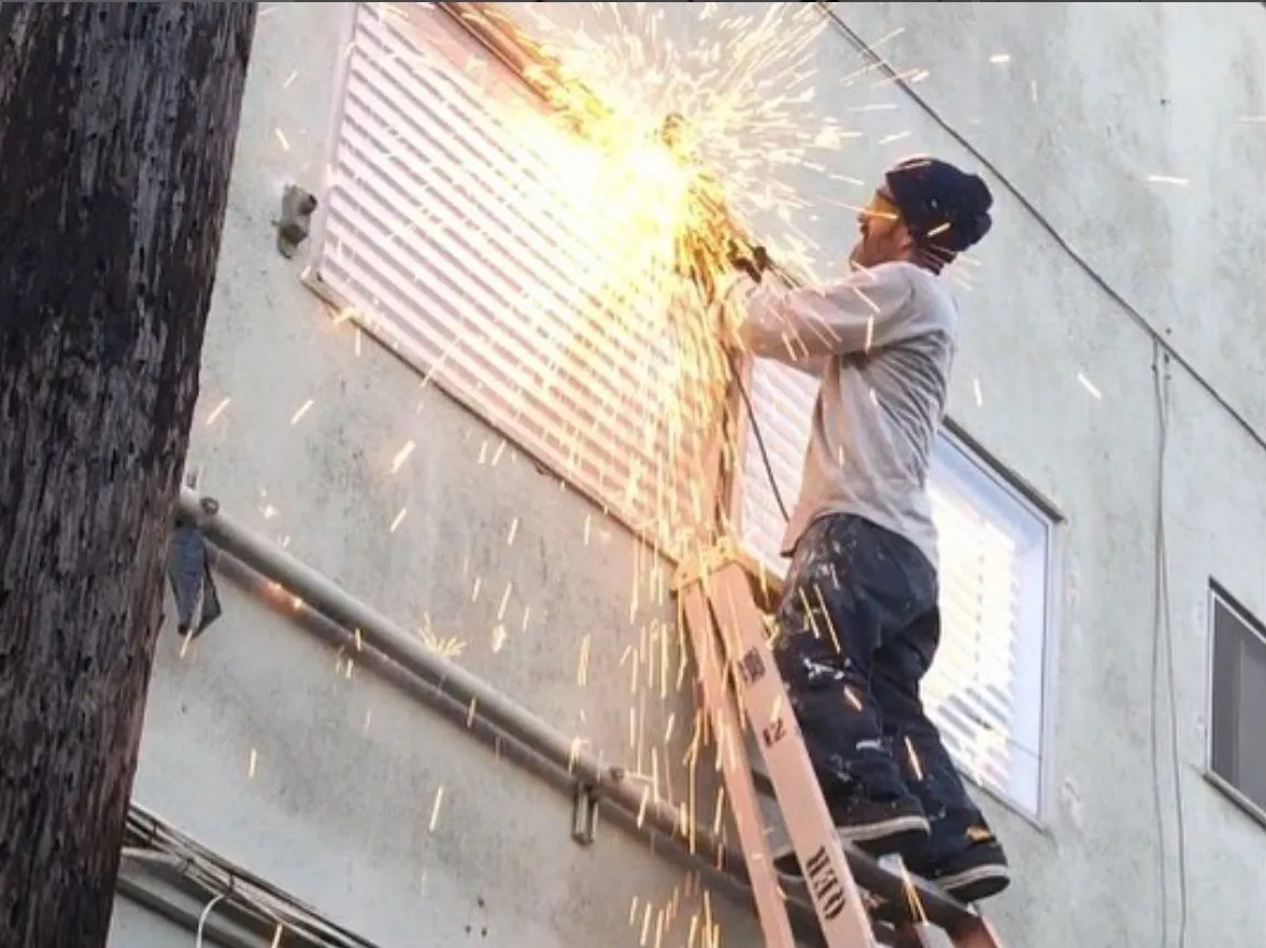Mario grinding a steel window grille on a ladder, sparks flying